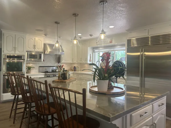a kitchen with stainless steel appliances granite countertop a dining table chairs and white cabinets