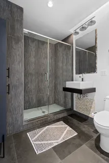 a bathroom with a sink a toilet a mirror and shower