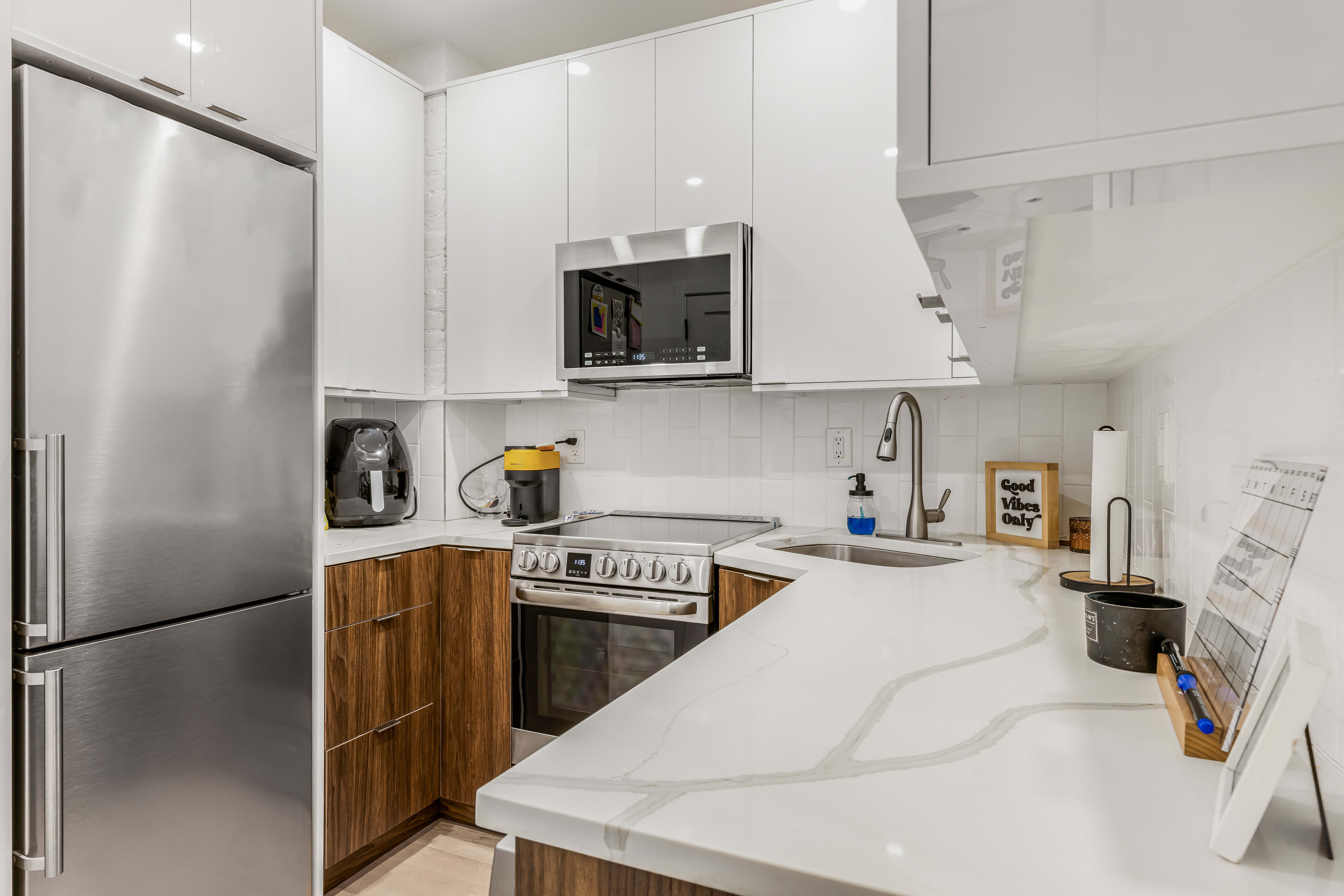 501 1/2 East 83rd Street, Unit 5E Manhattan, NY 10028 - Photo 2 of 7 a kitchen with stainless steel appliances a refrigerator a sink a stove and white cabinets