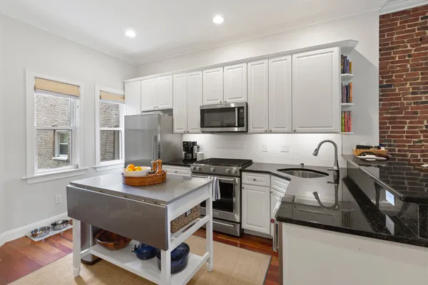 a kitchen with stainless steel appliances granite countertop a stove a sink dishwasher and a microwave with wooden floor