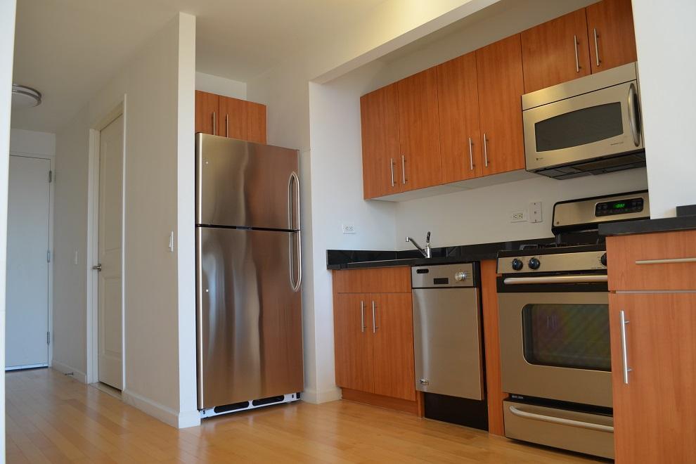 20 West Street, Unit 43E Manhattan, NY 10004 - Photo 3 of 10 a kitchen with stainless steel appliances granite countertop a refrigerator and a stove top oven