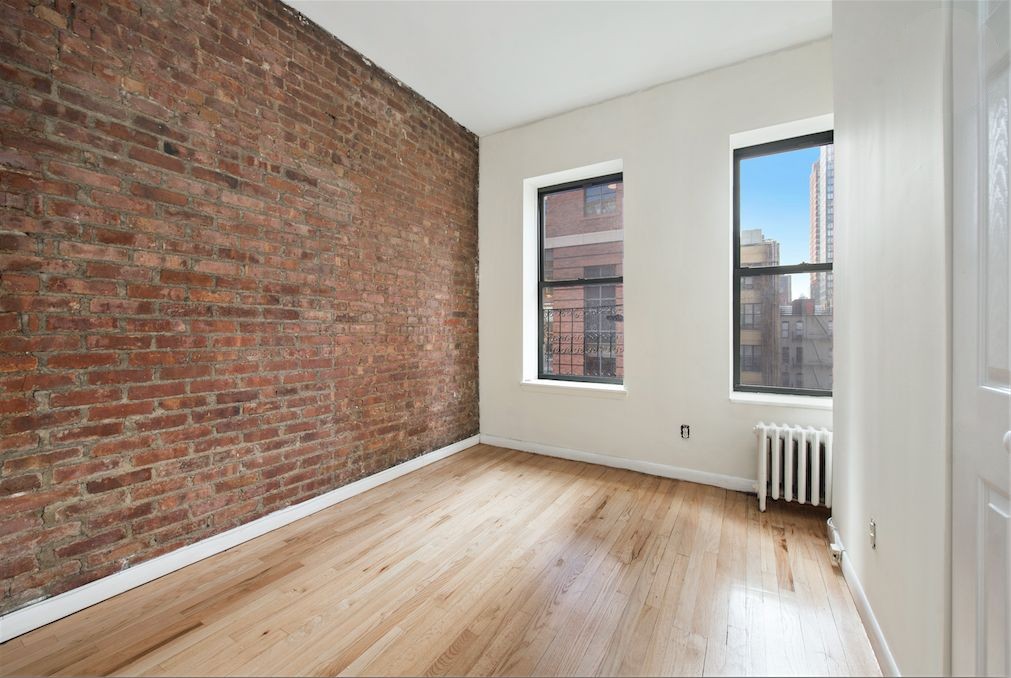 309 East 95th Street, Unit 27 Manhattan, NY 10128 - Photo 6 of 8 a view of an empty room with wooden floor and a window
