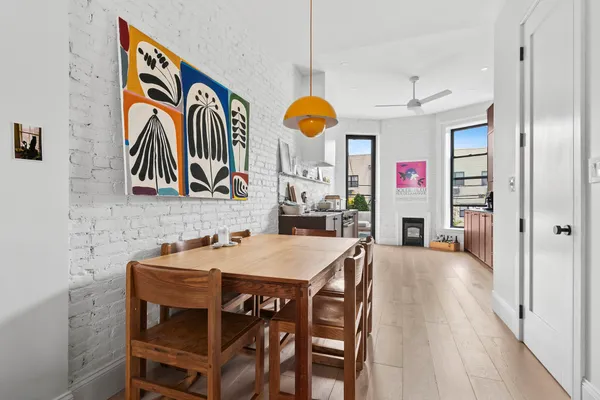 a very nice looking dining room with kitchen island furniture a chandelier fan and a wooden floor