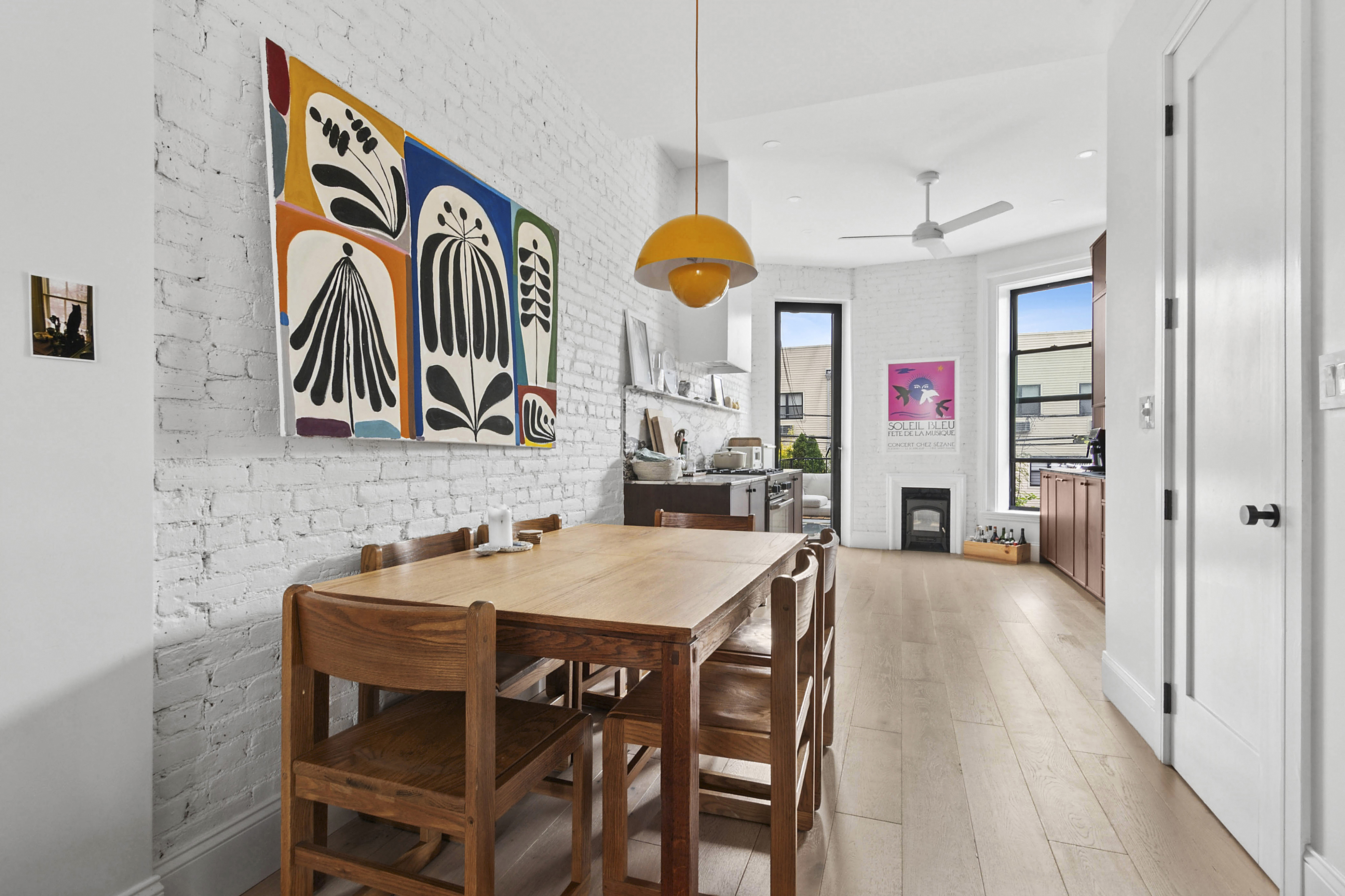a very nice looking dining room with kitchen island furniture a chandelier fan and a wooden floor