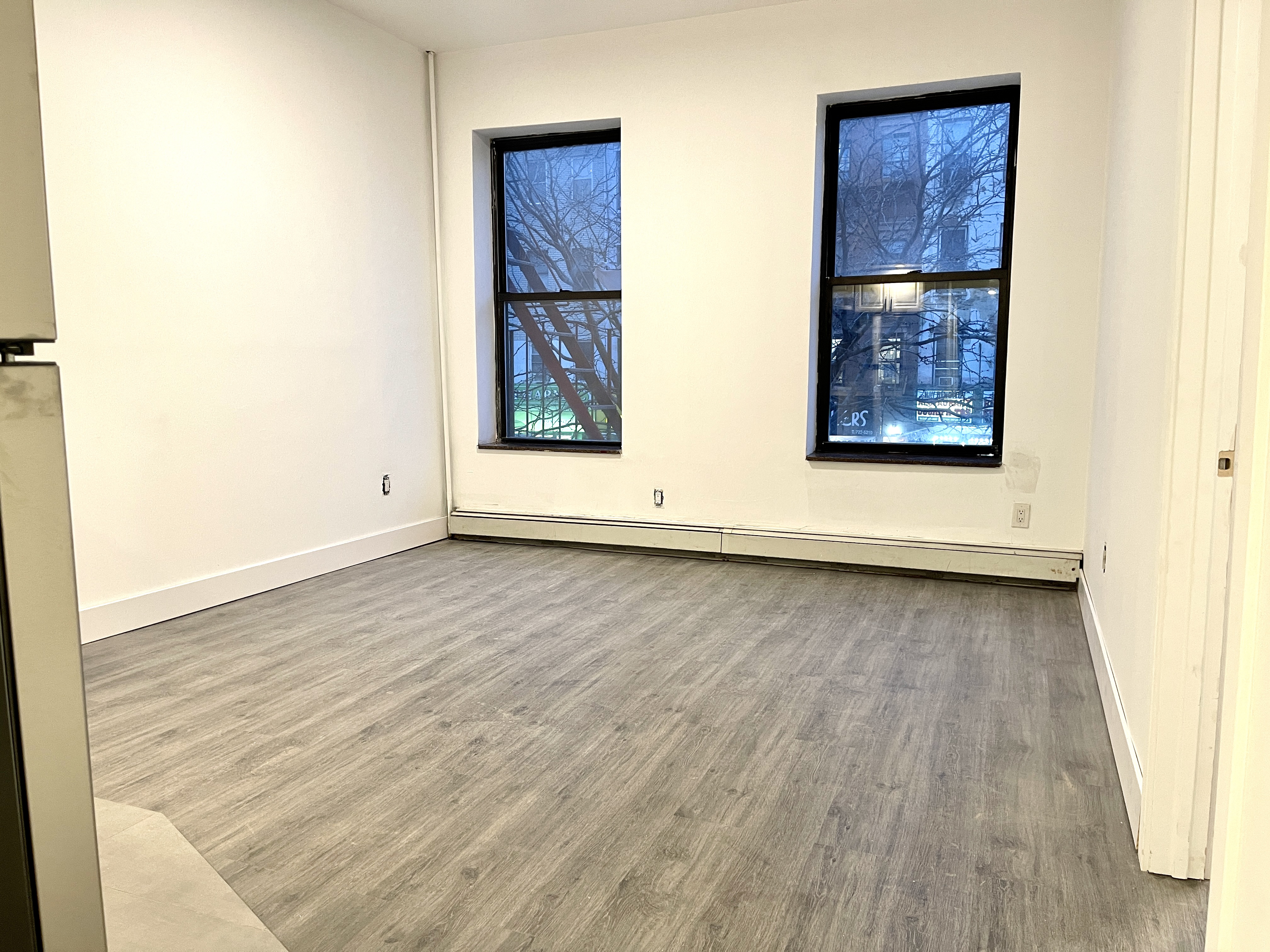 1999 3rd Avenue, Unit 1 Manhattan, NY 10029 - Photo 11 of 23 an empty room with wooden floor and windows