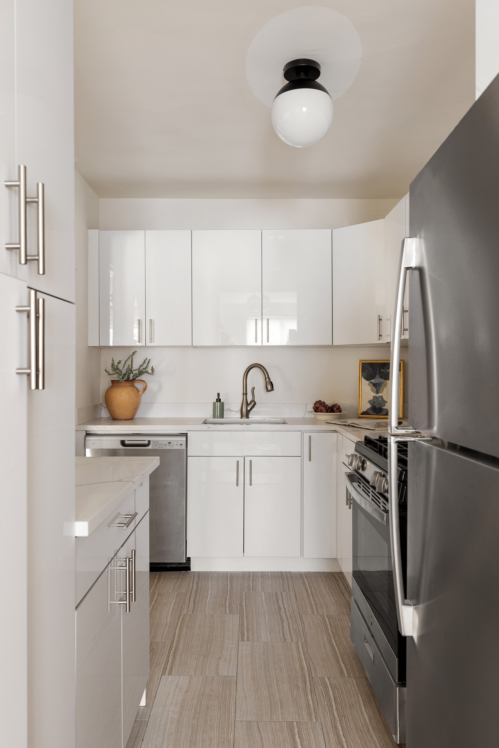 345 East 73rd Street, Unit 9H Manhattan, NY 10021 - Photo 6 of 13 a kitchen with white cabinets stainless steel appliances and a sink