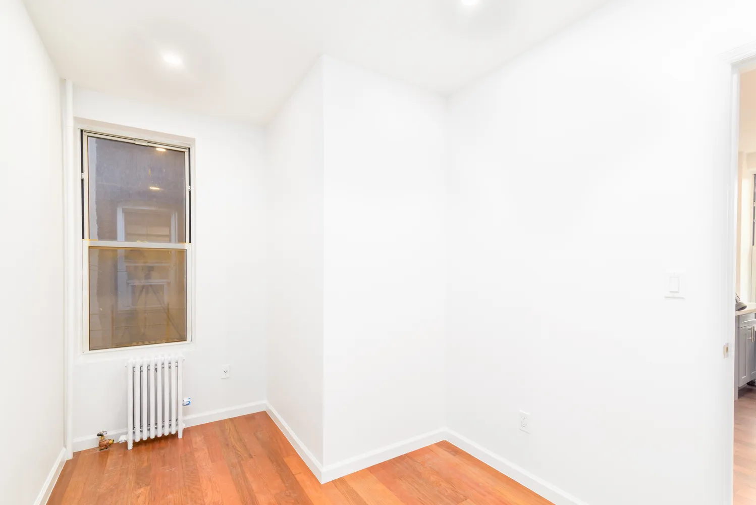 a view of a room with wooden floor and a window