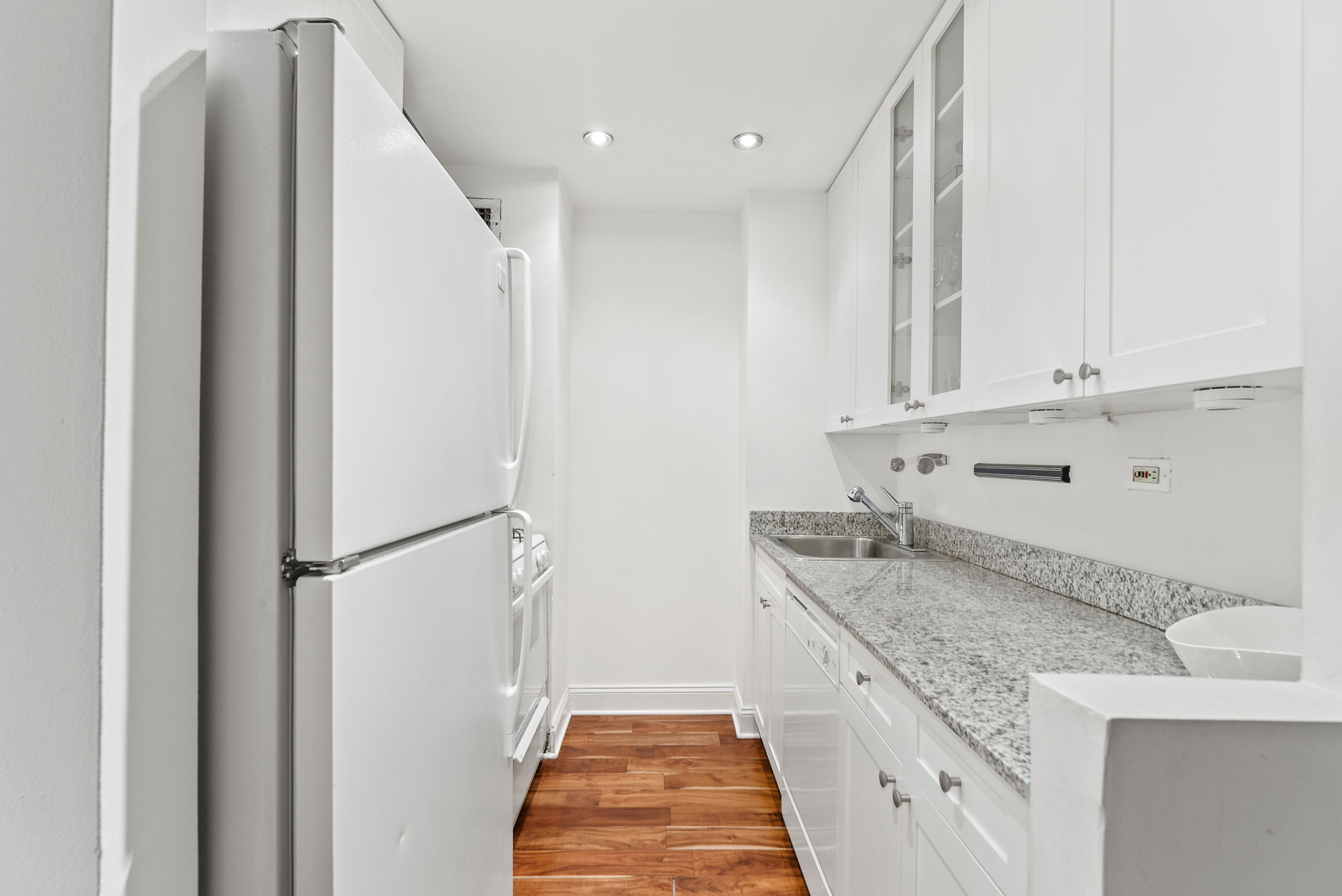 310 East 46th Street, Unit 5T Manhattan, NY 10017 - Photo 6 of 13 a kitchen with granite countertop a sink and refrigerator