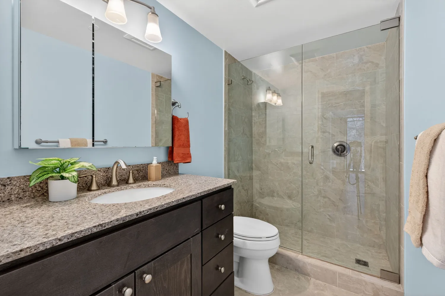 a bathroom with a granite countertop sink a toilet and shower