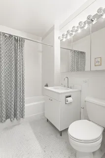 a bathroom with a toilet a sink a mirror a bathtub and shower