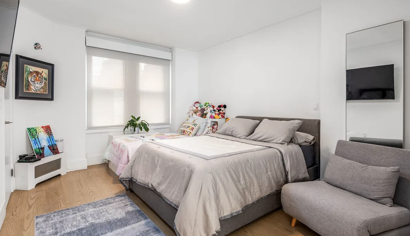 179 East 79th Street, Unit 1B Manhattan, NY 10075 - Photo 5 of 8 a spacious bedroom with a bed a couch and a flat screen tv