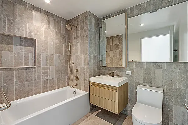 208 Delancey Street, Unit 10C Manhattan, NY 10002 - Photo 5 of 10 a bathroom with a toilet a sink a mirror a bathtub and shower