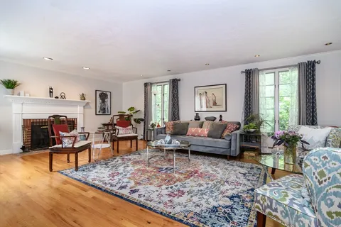 a living room with furniture large window and wooden floor