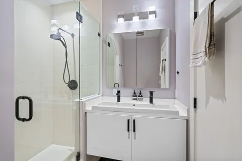 a bathroom with a double vanity sink mirror and shower