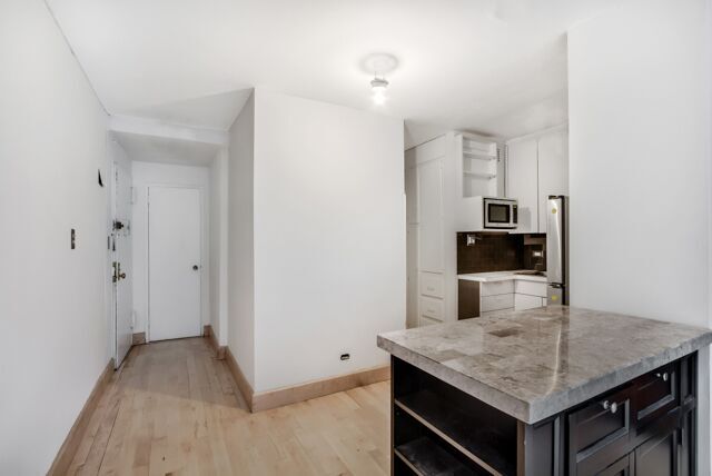 320 East 54th Street, Unit 4A Manhattan, NY 10022 - Photo 3 of 5 a kitchen with stainless steel appliances granite countertop a sink and refrigerator