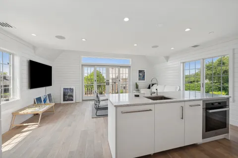 a kitchen with stainless steel appliances granite countertop a stove a sink a refrigerator and white cabinets with wooden floor