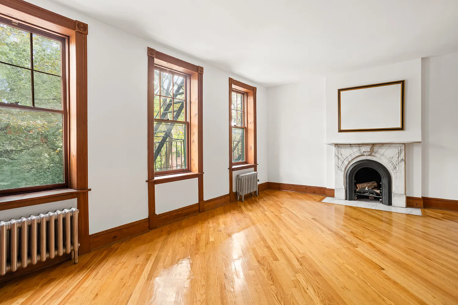 a view of an empty room with window and wooden floor