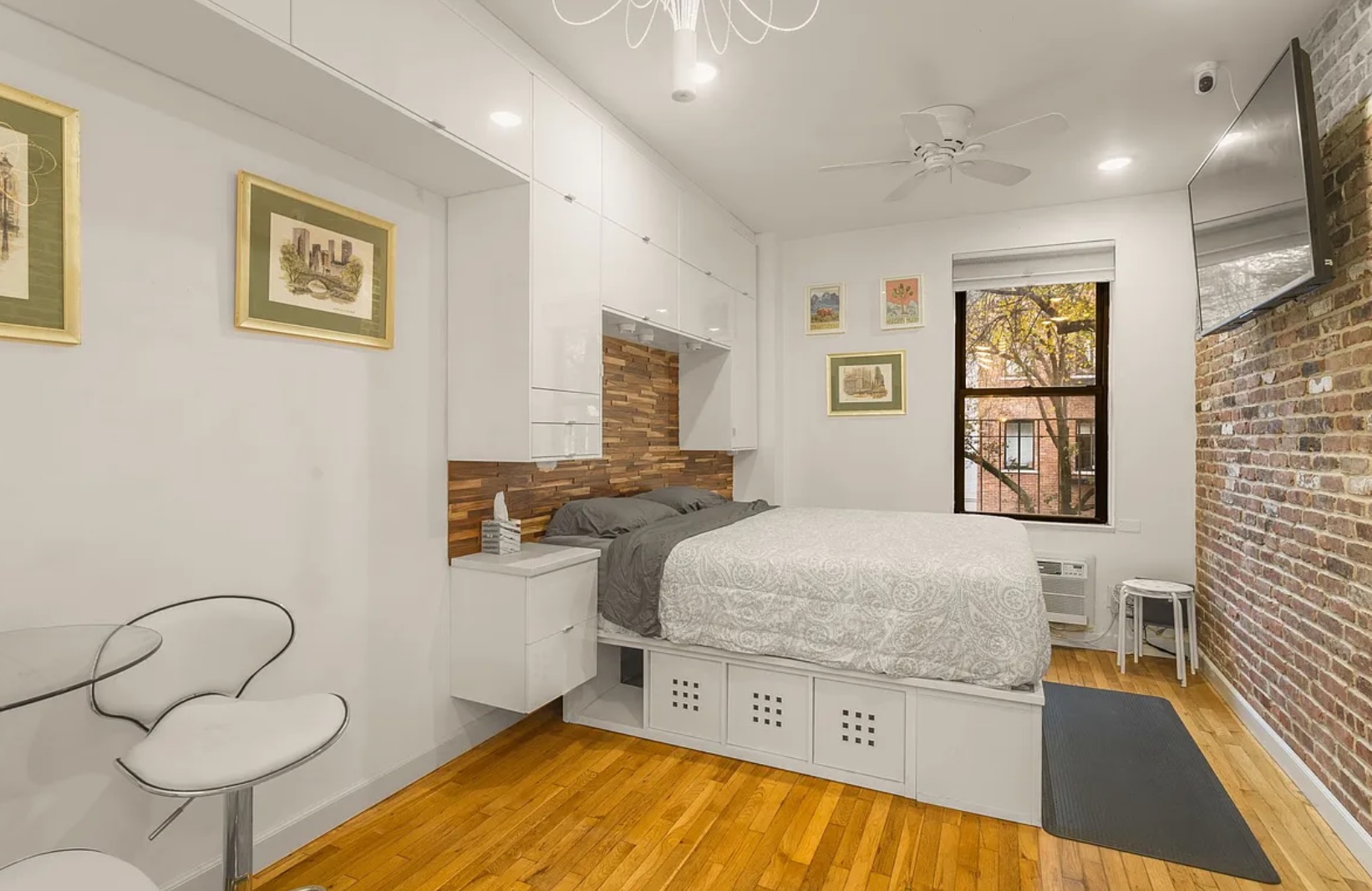 a bedroom with a bed and dresser with wooden floor