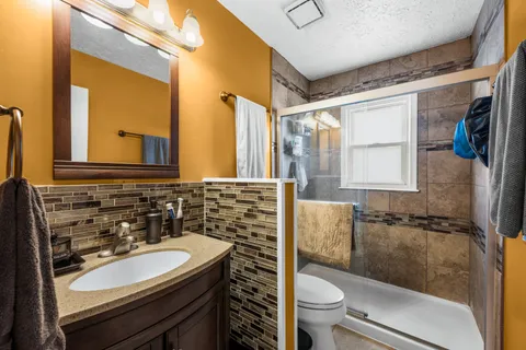 a bathroom with a sink a toilet a mirror and shower