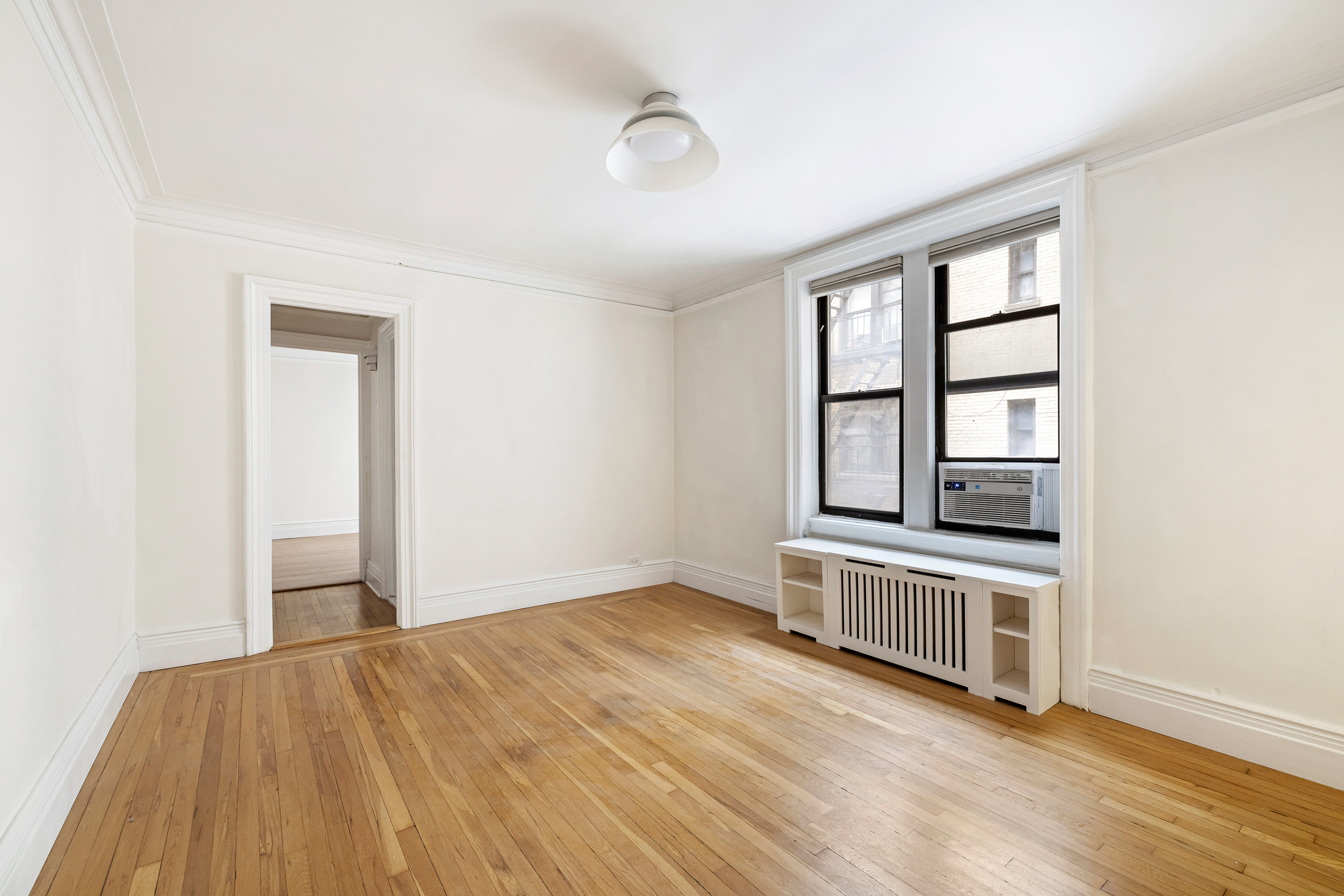 319 West 18th Street, Unit 2I Manhattan, NY 10011 - Photo 2 of 15 an empty room with wooden floor and windows