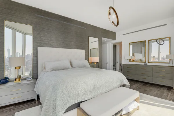 a bedroom with a bed a chandelier and dresser