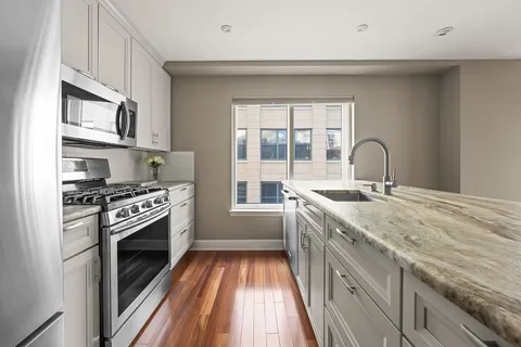 a kitchen with granite countertop a sink stainless steel appliances and cabinets