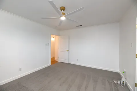 an empty room with ceiling fan and window
