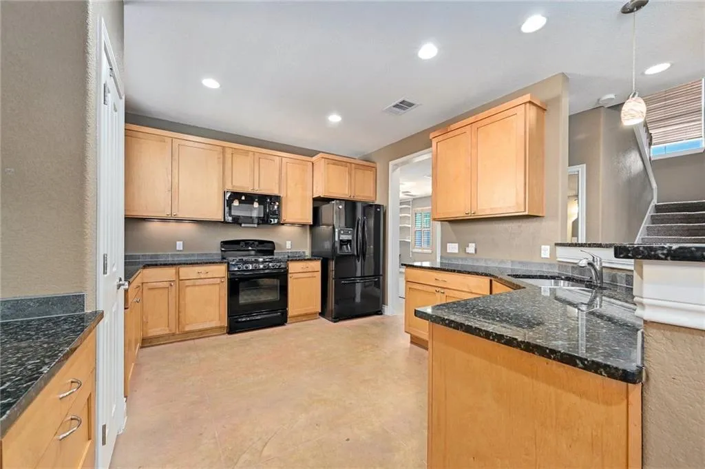 a kitchen with granite countertop stainless steel appliances a refrigerator sink stove microwave and cabinets
