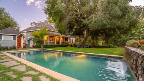 a view of pool with large trees and plants