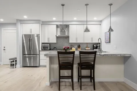 a kitchen with kitchen island a refrigerator stove microwave and white cabinets