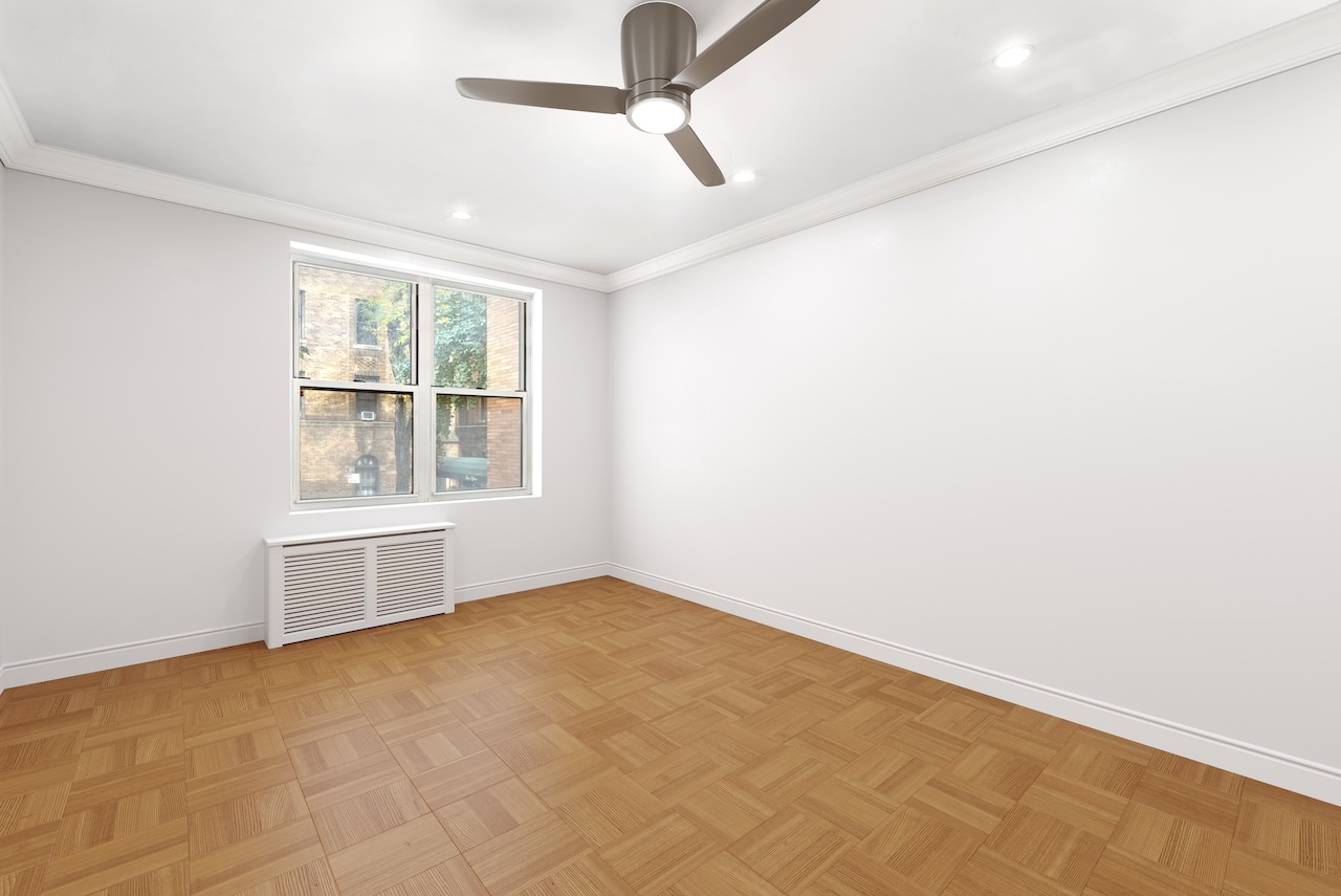 302 East 88th Street, Unit 2G Manhattan, NY 10128 - Photo 12 of 16 an empty room with chandelier fan and windows
