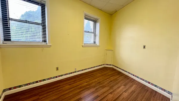a view of a room with wooden floor and small window