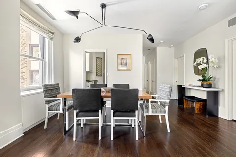 a dining room with wooden floor a chandelier a wooden table and chairs