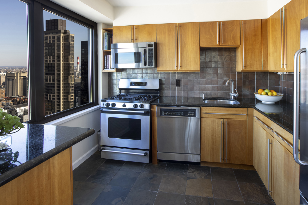 300 East 59th Street, Unit 3105 Manhattan, NY 10022 - Photo 6 of 21 a kitchen with stainless steel appliances a stove a sink and a refrigerator