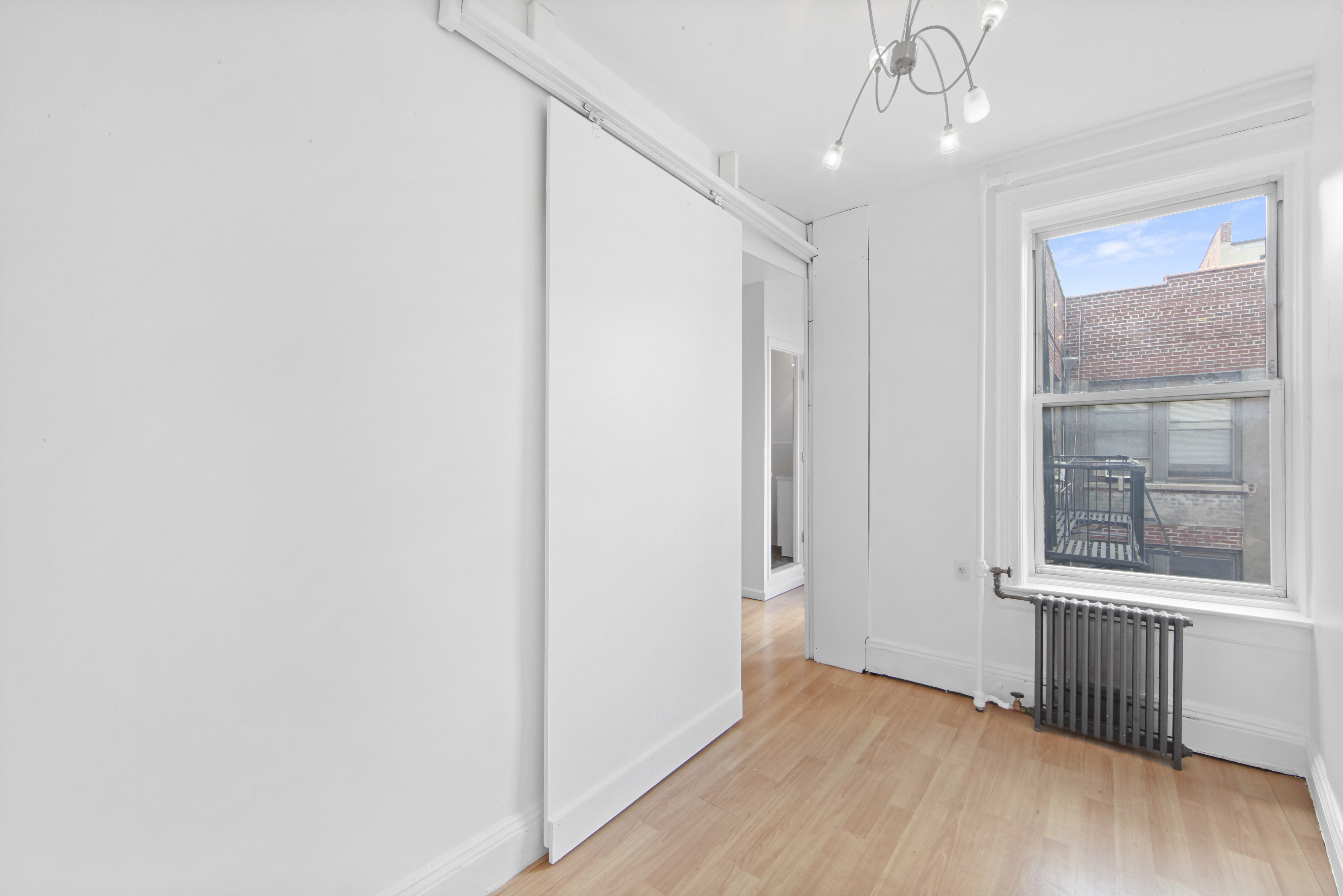 150 Sullivan Street, Unit 37 Manhattan, NY 10012 - Photo 4 of 12 a view of an empty room with wooden floor and a window