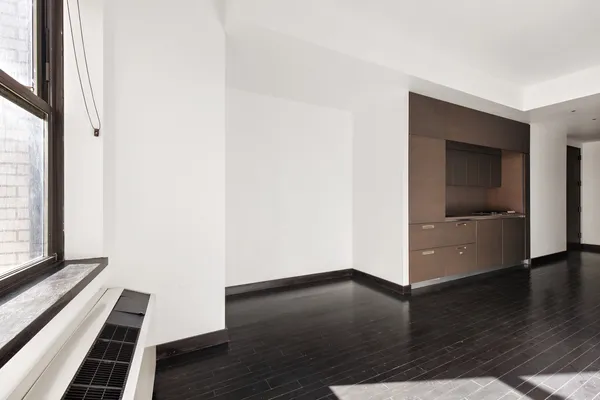 an empty room with wooden floor staircase and windows