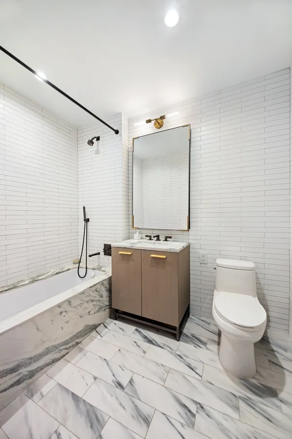 a bathroom with a granite countertop toilet sink and mirror
