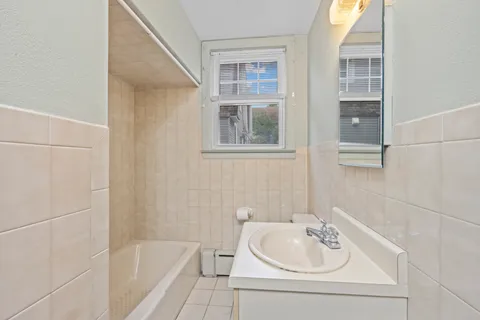 a bathroom with a tub sink and mirror