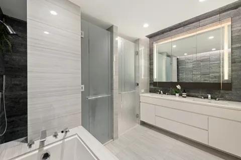 a bathroom with a double vanity sink mirror and bathtub