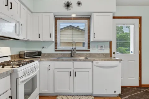 a kitchen with granite countertop white cabinets and white appliances