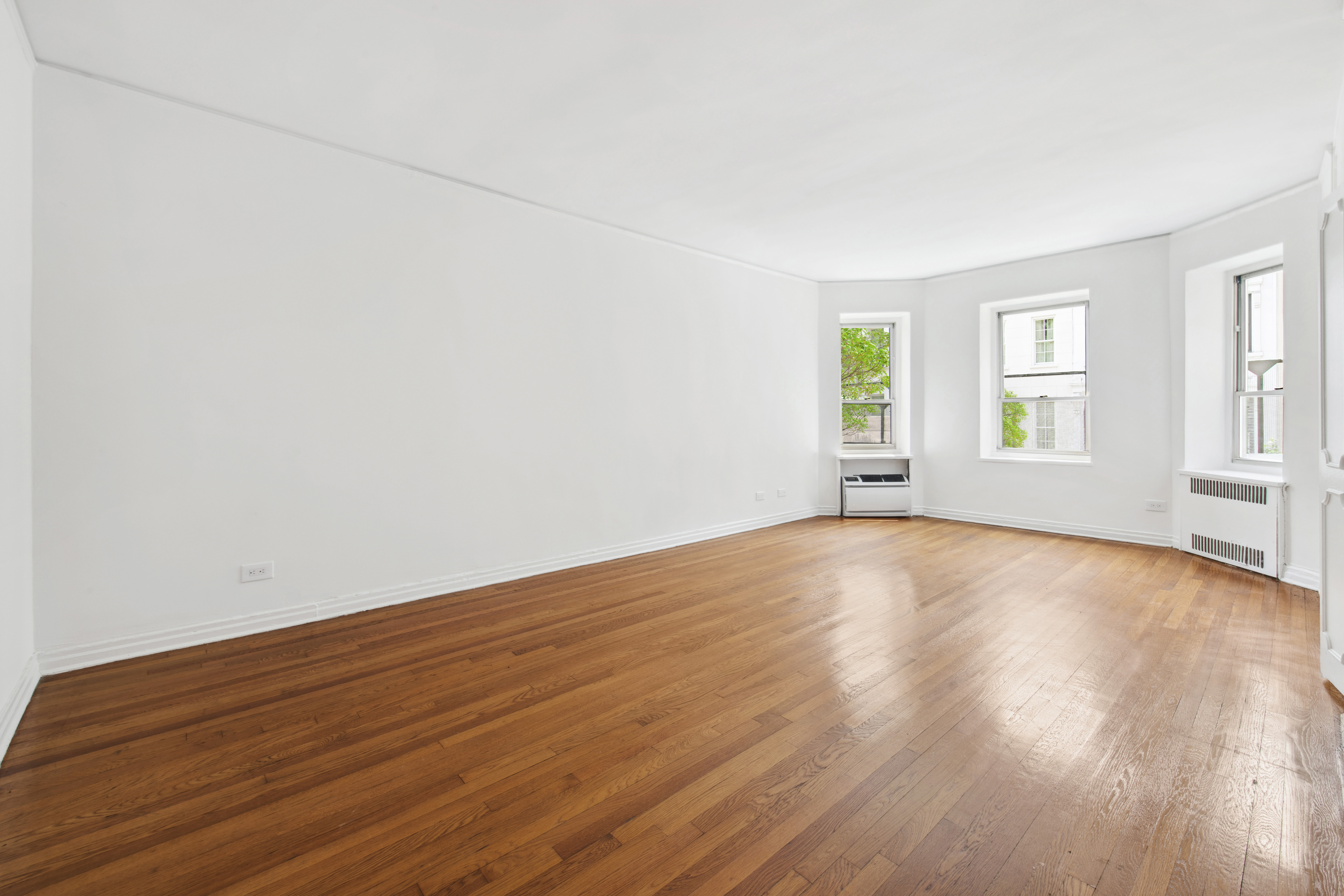 515 East 89th Street, Unit 2E Manhattan, NY 10128 - Photo 4 of 17 an empty room with wooden floor and windows