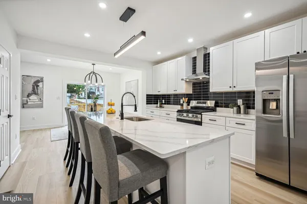 a kitchen with stainless steel appliances a refrigerator a stove a sink a dining table and chairs