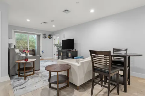 a living room with furniture a flat screen tv and a refrigerator