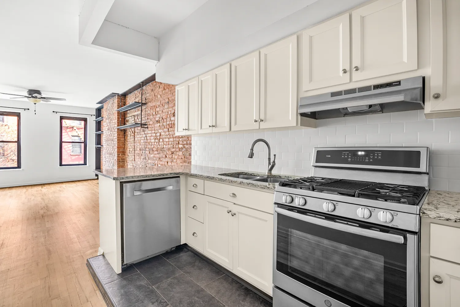 a kitchen with stainless steel appliances granite countertop a stove a sink and white cabinets