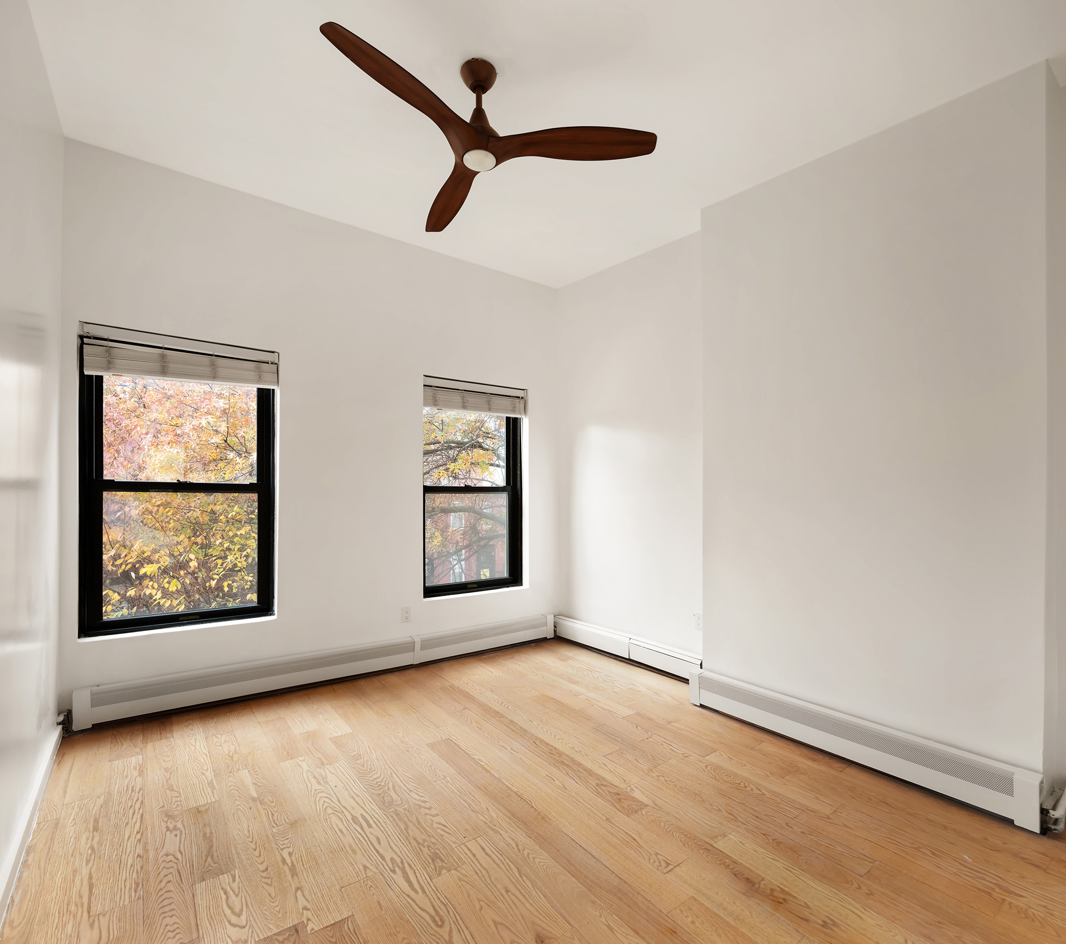 106 Monroe Street, Unit 2 Brooklyn, NY 11216 - Photo 3 of 6 an empty room with windows and ceiling fan