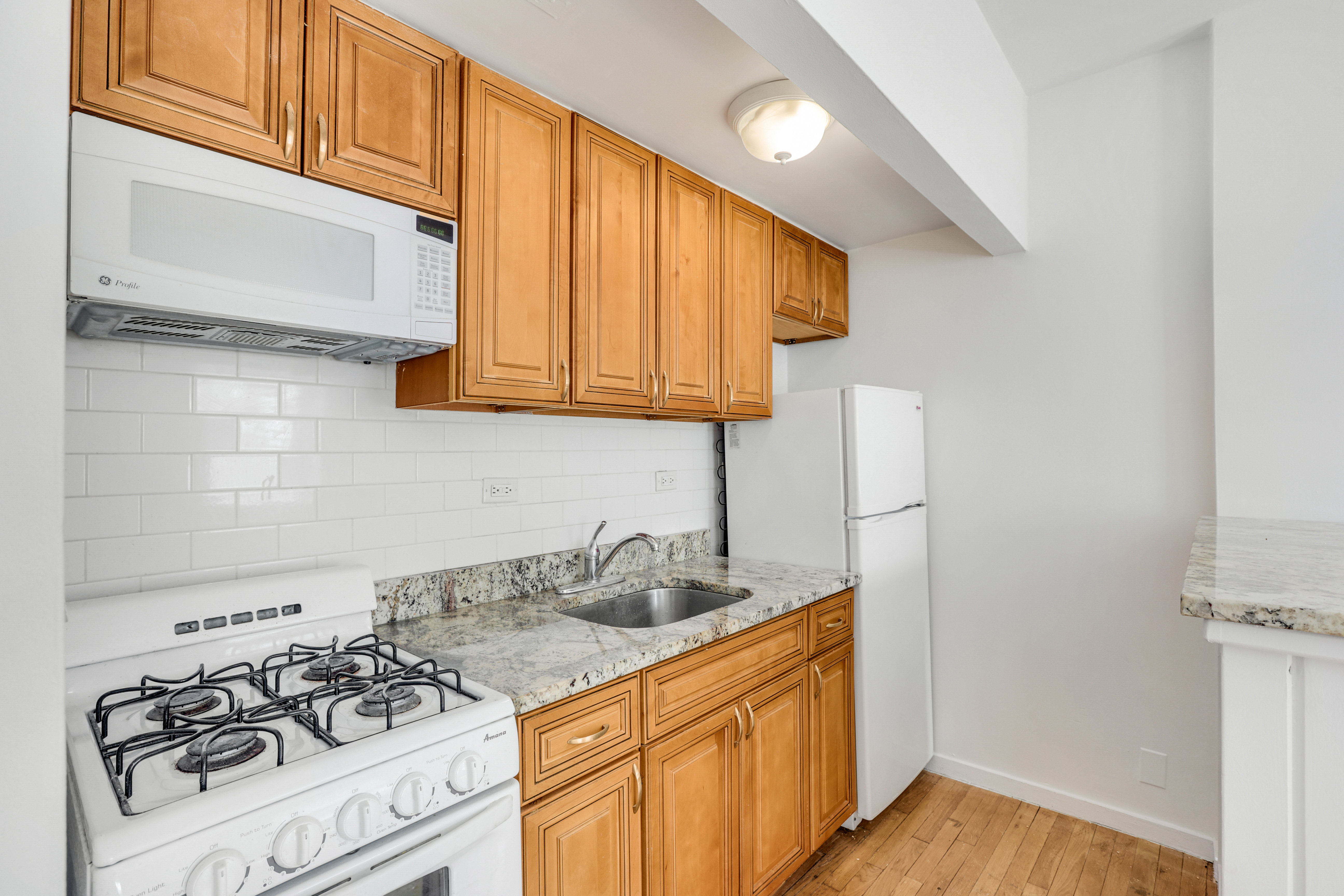 141 West 94th Street, Unit 1F Manhattan, NY 10025 - Photo 5 of 9 a kitchen with stainless steel appliances granite countertop white cabinets and a stove top oven