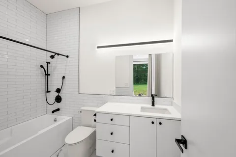 a bathroom with a bathtub shower sink mirror vanity and toilet
