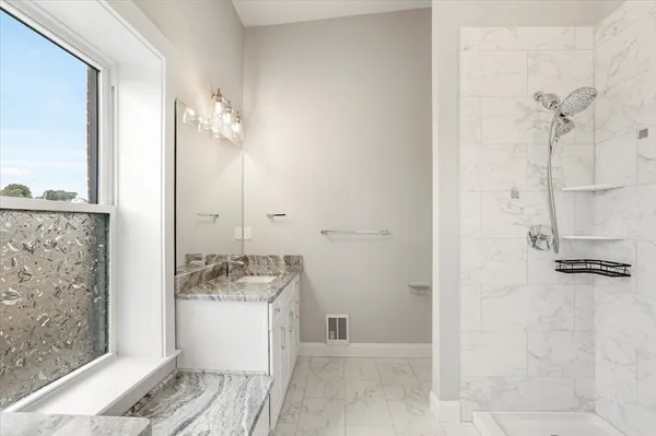 a bathroom with a granite countertop sink a mirror and shower