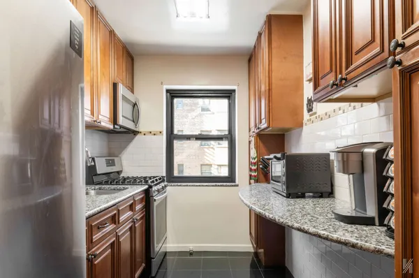 a kitchen with stainless steel appliances granite countertop a refrigerator a stove and a sink with wooden floor