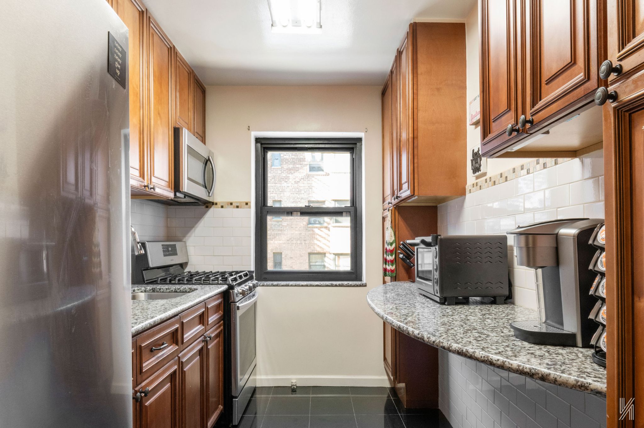 34-10 94th Street, Unit 3D Queens, NY 11372 - Photo 6 of 17 a kitchen with stainless steel appliances granite countertop a refrigerator a stove and a sink with wooden floor